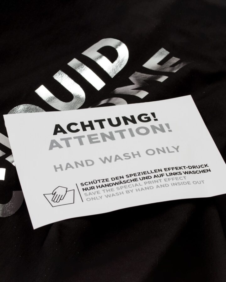 Warnhinweis liegt auf einem schwarzen Hoodie mit glänzender, reflektierender Schrift als Front-Print