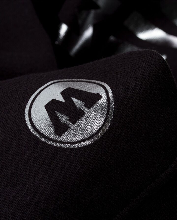 Nahaufnahme von silbern reflektierendem Logo auf dem Ärmel eines schwarzen Pullovers