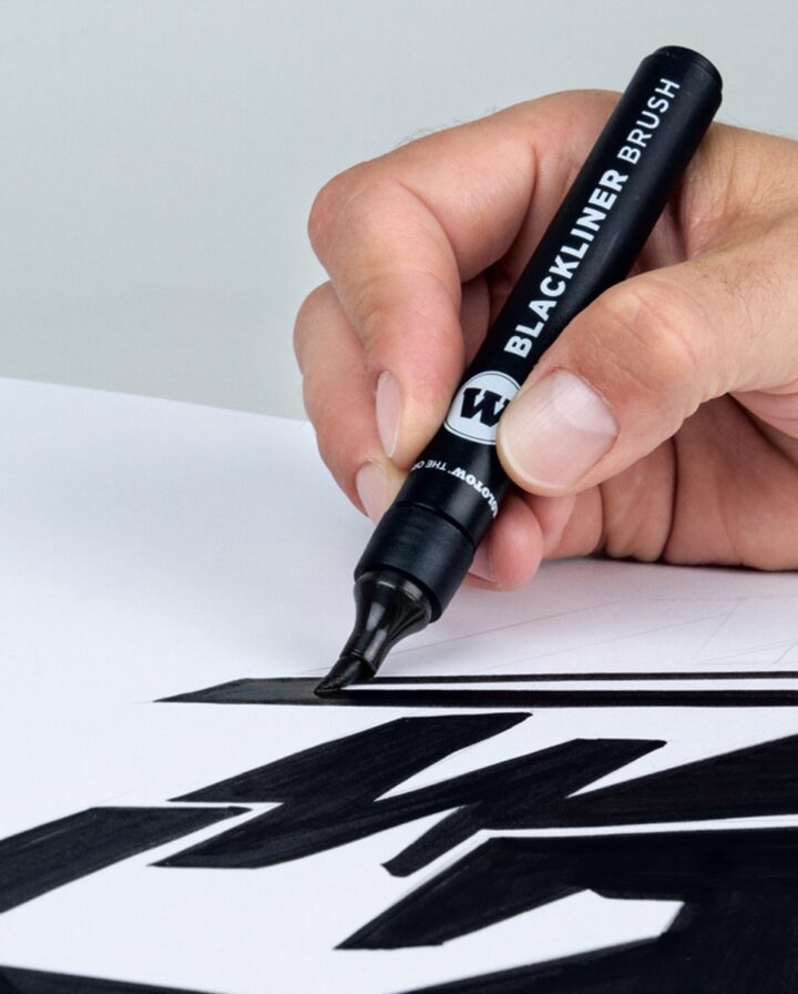 Hand mit schwarzem Pinselstift malt schwarze Flächen auf ein weißes Blatt