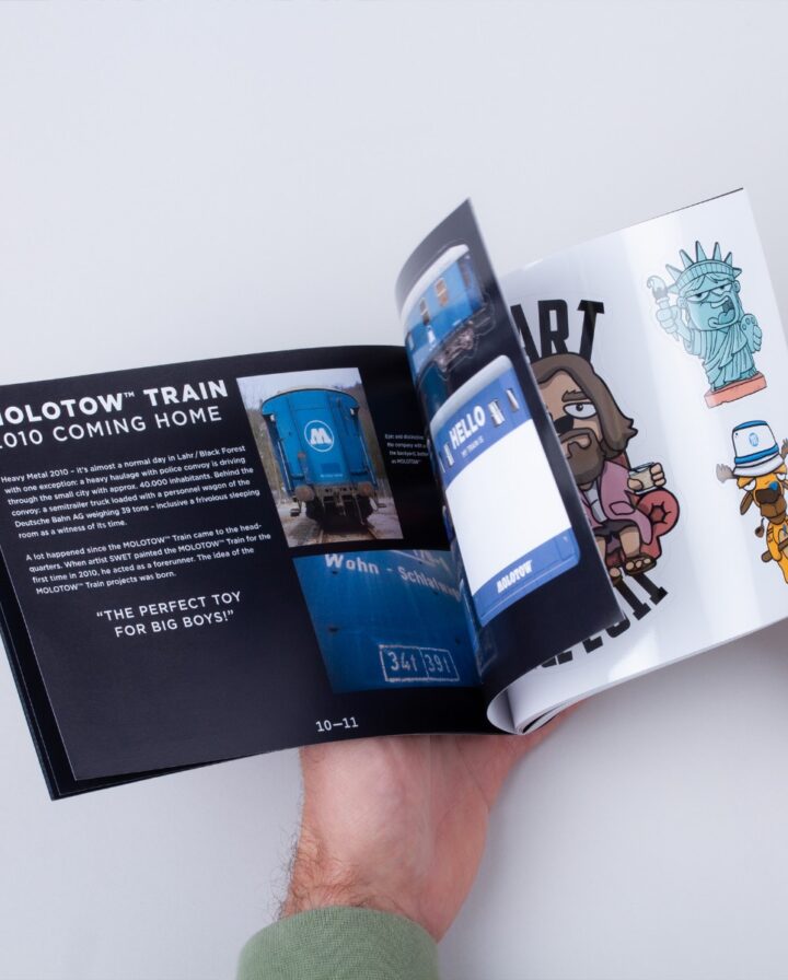 Ein Foto, bei dem ein kleines Magazin, mit Infotexten und Stickern befüllt, per Hand durchgeblättert wird
