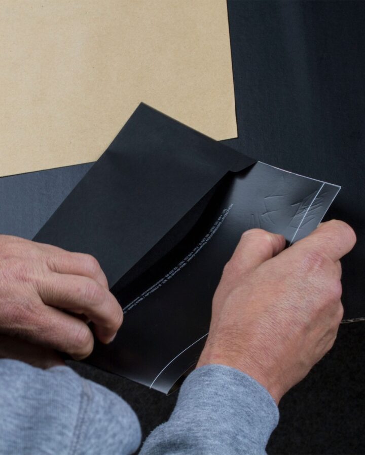 Foto von einem Mann, der einen beschrifteten Molotow-Gutschein in einem schwarzen Umschlag steckt