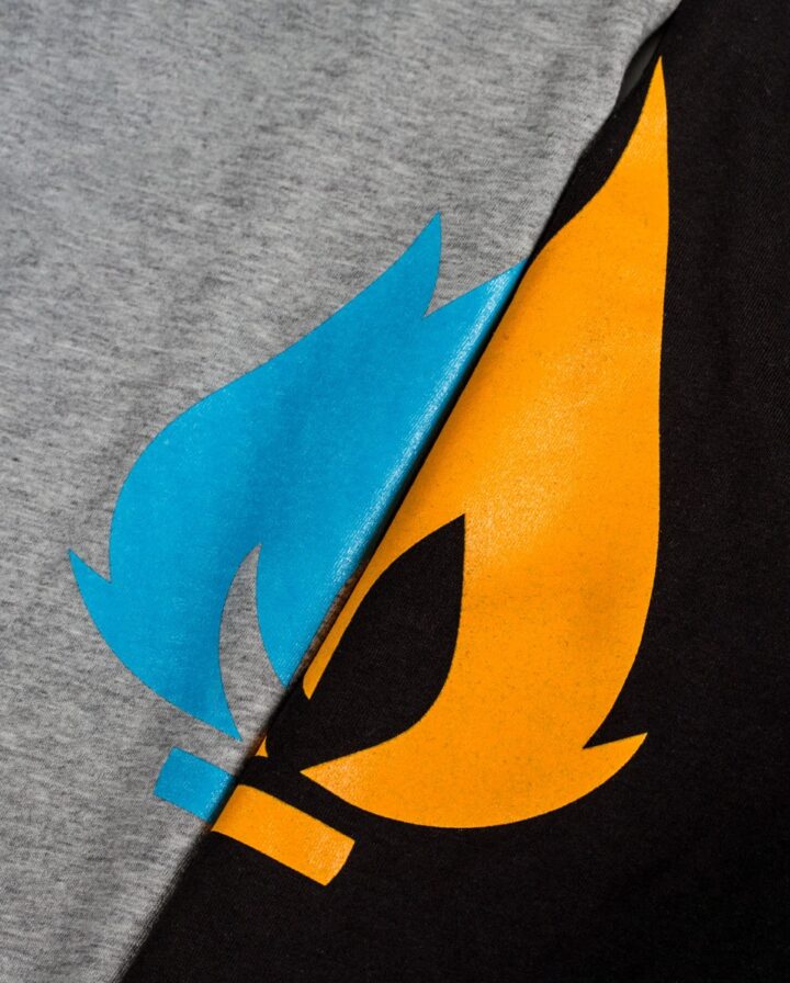 Foto von zwei übereinander gelegte T-Shirts in schwarz und Grau mit oranger und blauer Flamme als Print auf der Brust