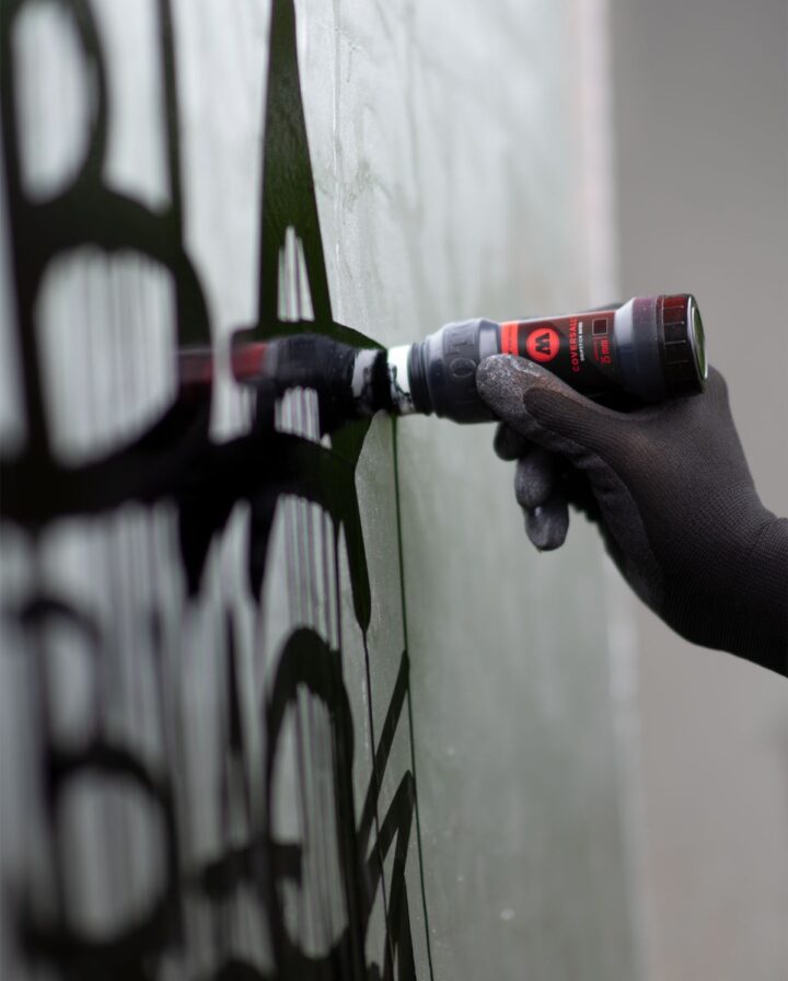 Anwendung eines Coversall Dripsticks in Schwarz auf chrome besprühter Wand
